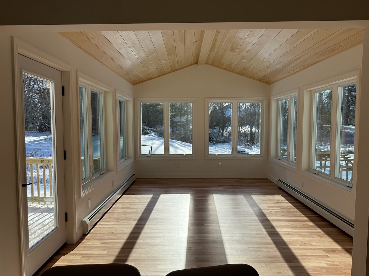 Bright sunroom addition with wood ceiling and large windows by Maine General Contractors